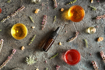 Dark background with bottles of aromatherapy essential oil with frankincense, thyme and other herbs...