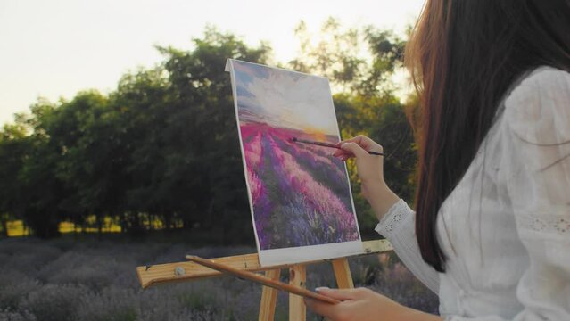 In the midst of a serene summer field, a caucasian woman draws inspiration from the colorful lavender, creating a beautiful painting that captures the essence of nature's artistic allure.