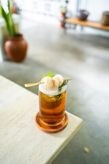 Fresh cold drink of lychee tea on a table with an elegant cafe in the background.