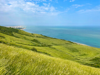 Picturesque green hilly coastline of South England above the turquoise blue sea