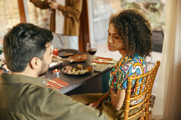 Friends enjoying in conversation and drinking wine during festive dinner at home party