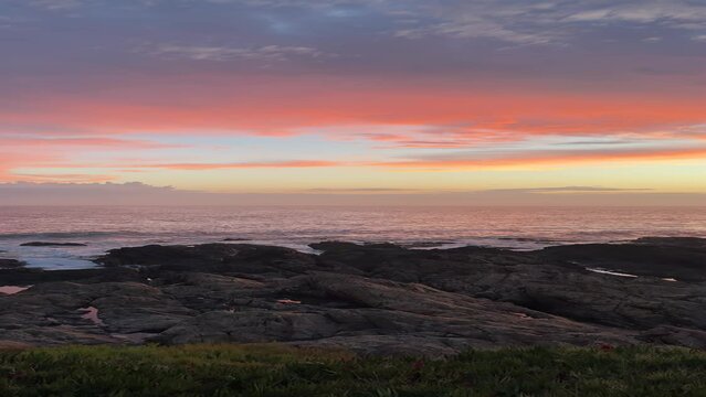 A beautiful sunset in front of the sea and rocks with pink hues in Punta del Este, Uruguay.