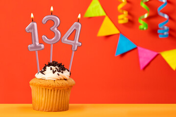 Birthday cupcake with number 134 candle - Sparkling orange background with bunting