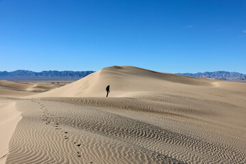 Lone hiker explores the desert sand dunes