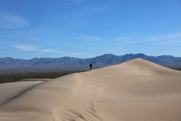 Lone hiker explores the desert sand dunes