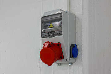 Outdoor Electrical Box with Single and Three Phase Current Electrical Appliances and Power Outlets. Three phase connectors. In a factory hall, red and blue, 220 volt and 380 volt sockets. - obrazy, fototapety, plakaty