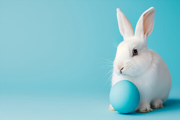 Easter bunny rabbit with painted egg on blue background