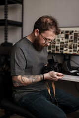 A focused man examines a medium format camera, immersed in the intricate art and technical...