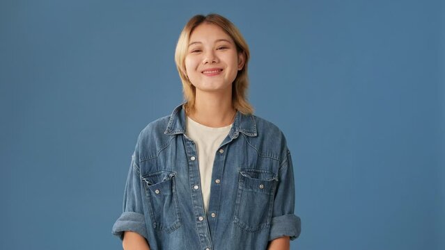 Young woman laughing looking at camera isolated on blue background
