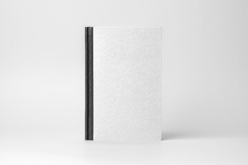 A hardcover book with a black spine is showcased upright against a white background, illuminated by soft studio light, highlighting its textured paper surface ready for your design