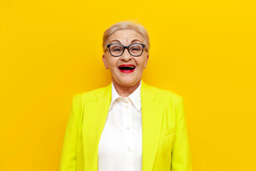 cheerful surprised old businesswoman in glasses and formal wear looking at camera with open mouth...