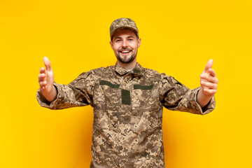 Ukrainian army soldier in pixel camouflage uniform hugs and raises his hands forward on a yellow...