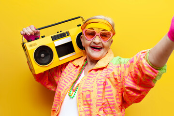 funny crazy granny in hipster clothes listening to music on tape recorder and taking selfie on...