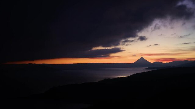 Time lapse of cloudy sunrise over Arenal volcano in central Costa Rica with nearby lake on the foreground