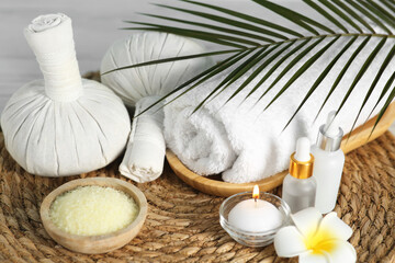 Composition with different spa products and plumeria flower on wicker mat