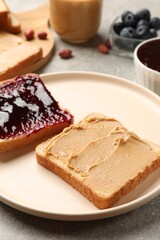 Tasty peanut butter sandwiches with jam on gray table, closeup