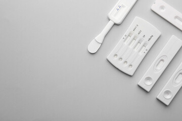 Different disposable express tests on light grey background, flat lay. Space for text