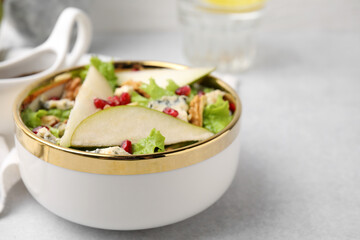 Delicious pear salad in bowl on light table, closeup. Space for text