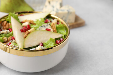 Delicious pear salad in bowl on light table, closeup. Space for text