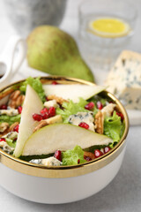 Delicious pear salad in bowl on light table, closeup