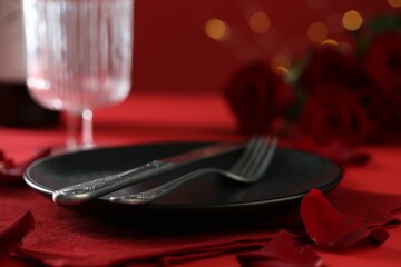 Place setting with roses on red table, closeup. Romantic dinner