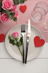 Romantic place setting with flowers and red paper hearts on white wooden table, flat lay. St. Valentine's day dinner