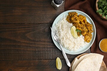 Delicious chicken curry with rice and ingredients on wooden table, flat lay. Space for text