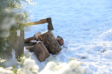 Fototapeta premium Metal axe in wooden log and pile of wood outdoors on sunny winter day. Space for text