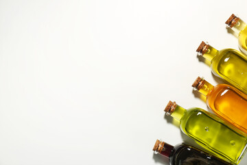 Vegetable fats. Different cooking oils in glass bottles on white background, flat lay. Space for...