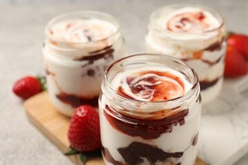 Tasty yoghurt with jam and strawberries on grey table, closeup