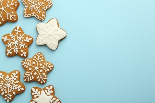 Tasty star shaped Christmas cookies with icing on light blue background, flat lay. Space for text