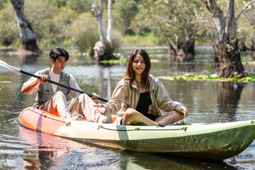 Asian attractive romantic young couple rowing kayak in a forest lake. 