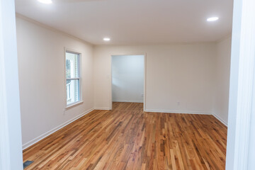 A house for sale with an empty white room of a newly renovated and painted house with dark hardwood floors