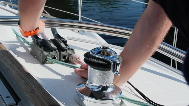 Seasoned yachtsman pulls durable nylon rope through sailboat cleat. Sailor prepares lines before sailing yacht in open waters