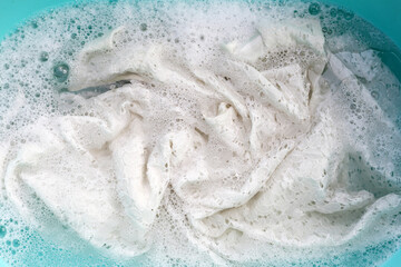 Women's lace dress soaked in water dissolved detergent with white foam bubble. Laundry concept