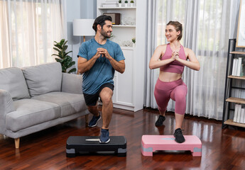 Athletic and sporty couple doing squat together during home body workout exercise session for fit...
