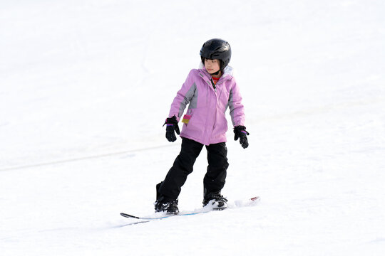 Young Asian female child on snowboard in action
