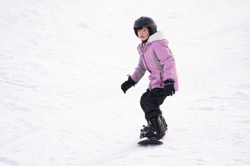 Fototapeta na wymiar Young Asian female child on snowboard in action