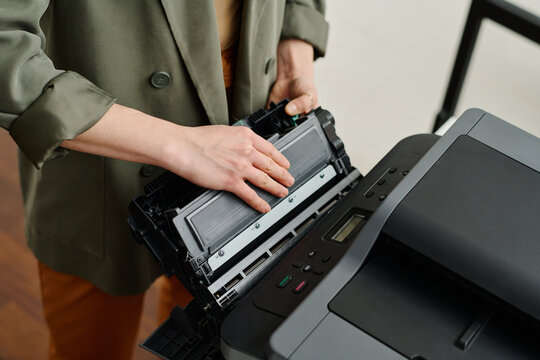 High angle view of unrecognizable female manager working in office taking out printer cartridge