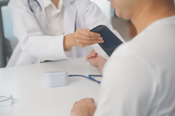 Male doctor uses a blood pressure monitor to check the body pressure and pulse of the patients who come to the hospital for check-ups, Medical treatment and health care concept.