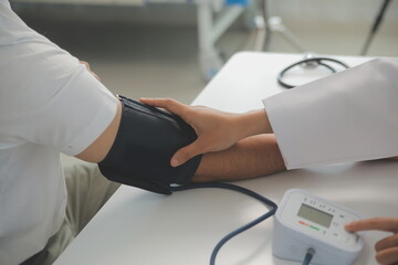 Male doctor uses a blood pressure monitor to check the body pressure and pulse of the patients who...