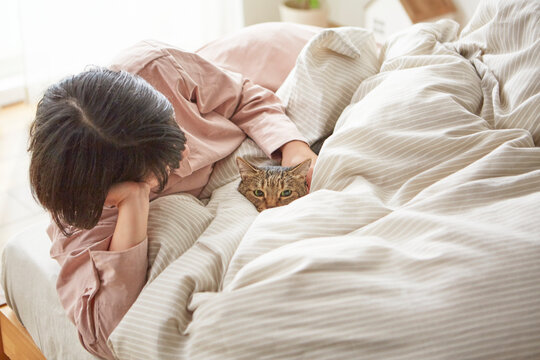 ベッドのうえで猫と戯れる女性