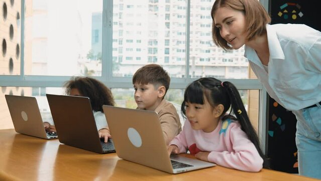 Smart teacher teaching and looking student using laptop at classroom. Professional instructor explained about programing engineering code or prompt while studying and learning program. Erudition.