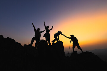 Silhouette Teamwork of four  hiker helping each other on top of mountain climbing team beautiful sunrise. Teamwork friendship hiking help each other trust assistance. climbing team success. - obrazy, fototapety, plakaty