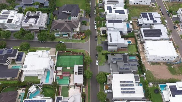 Reverse aerial flyover of architecturally-designed modern prestige homes (some still under construction) with rooftop solar and pools in outer suburban Sydney, Australia.