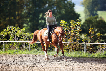 Horse woman rider riding in the sunshine at the riding arena.