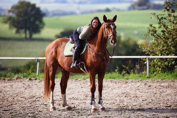 Horse woman rider riding in the sunshine at the riding arena.