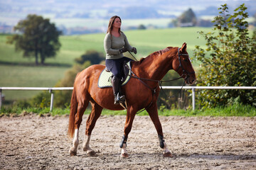 Horse woman rider riding in the sunshine at the riding arena.