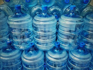 Stack of empty water bottles jugs in a warehouse, close up details. Purified water battles for...