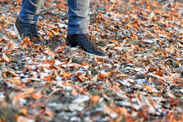 a man walks through the autumn leaves covered with snow